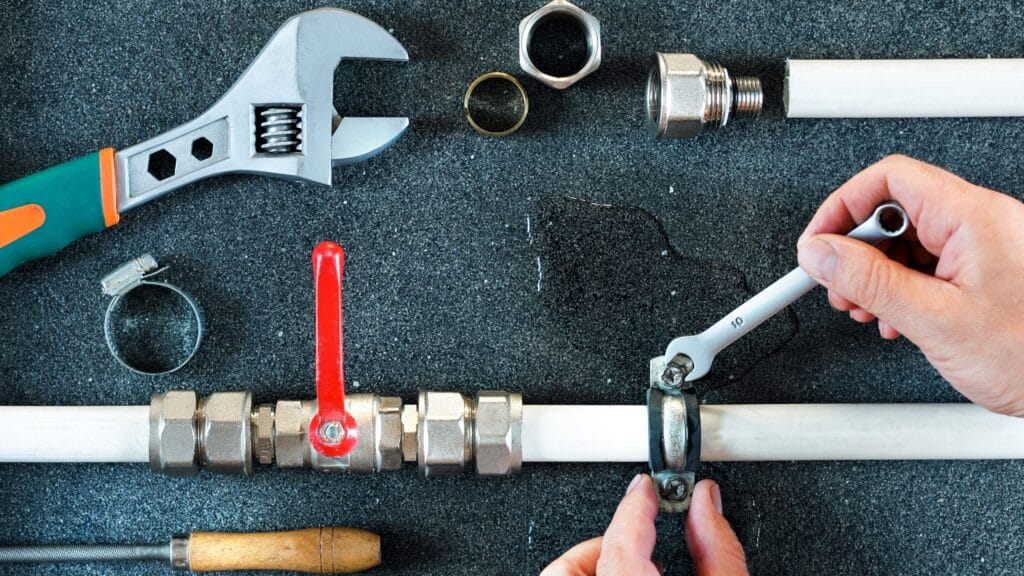 Plumber repairing a pipe valve with an adjustable wrench in Winter Springs