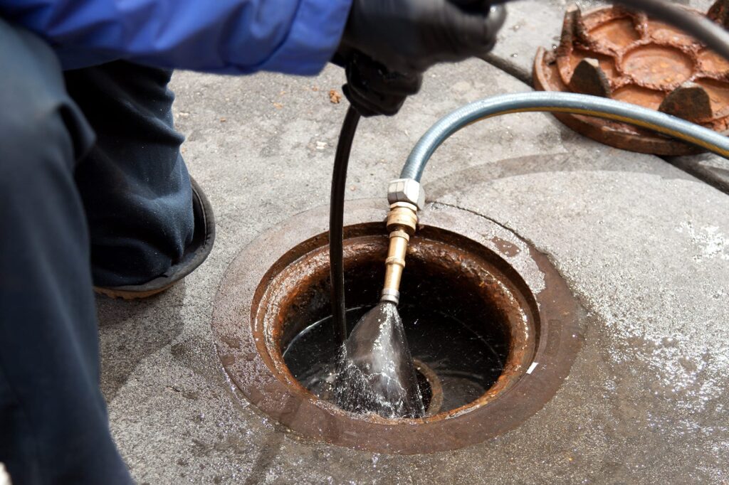 Plumber hydro jetting a sewer line through a manhole in Winter Springs