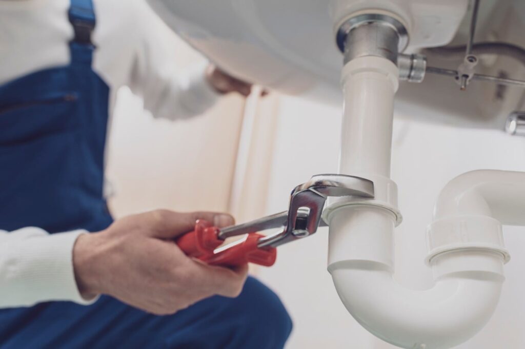 Plumber repairing a white drain pipe beneath a sink in Winter Springs