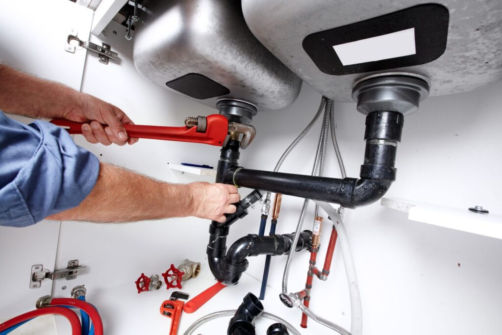 Plumber repairing drain pipes beneath a kitchen sink in Winter Springs