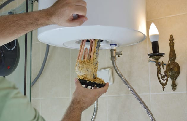 Technician removing mineral buildup from a water heater in Winter Springs