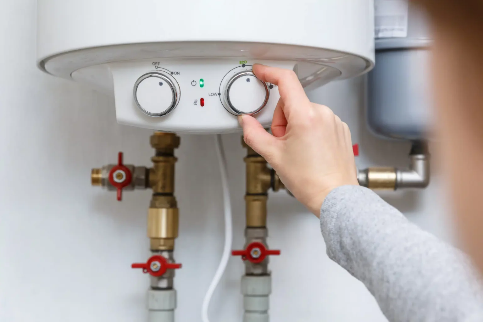 Homeowner adjusting the temperature controls on a water heater in Winter Springs